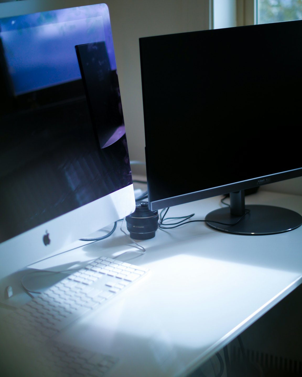 Two computer monitors and keyboard on a white desk.