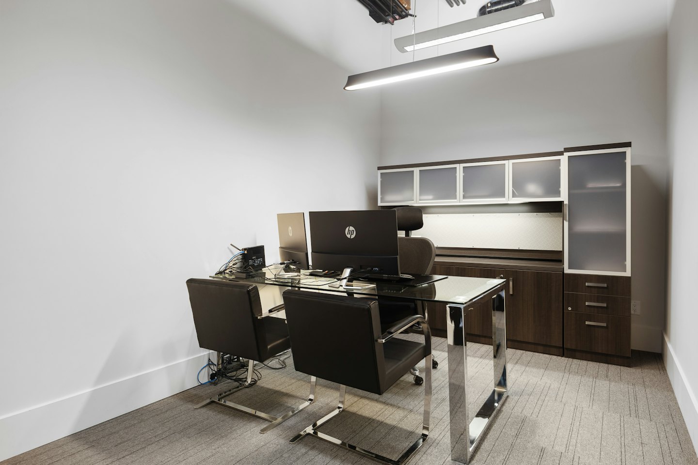 Modern office with glass desk and dual computer monitors.