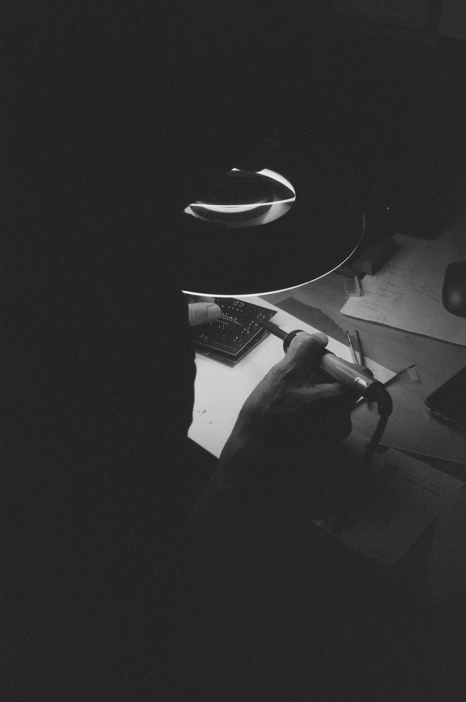 Hands soldering a circuit board with a tool.